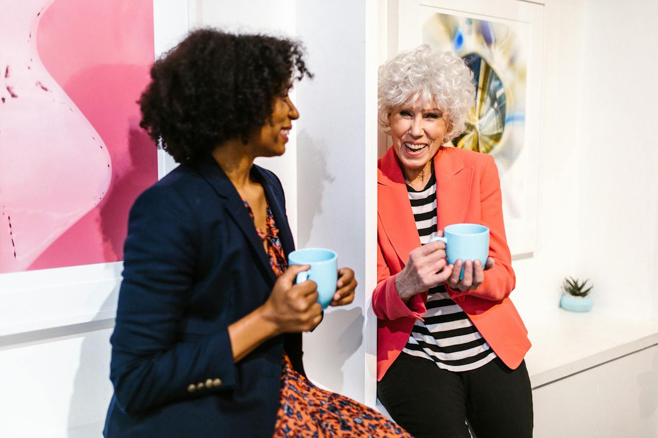 Two ladies holding mugs and laughing