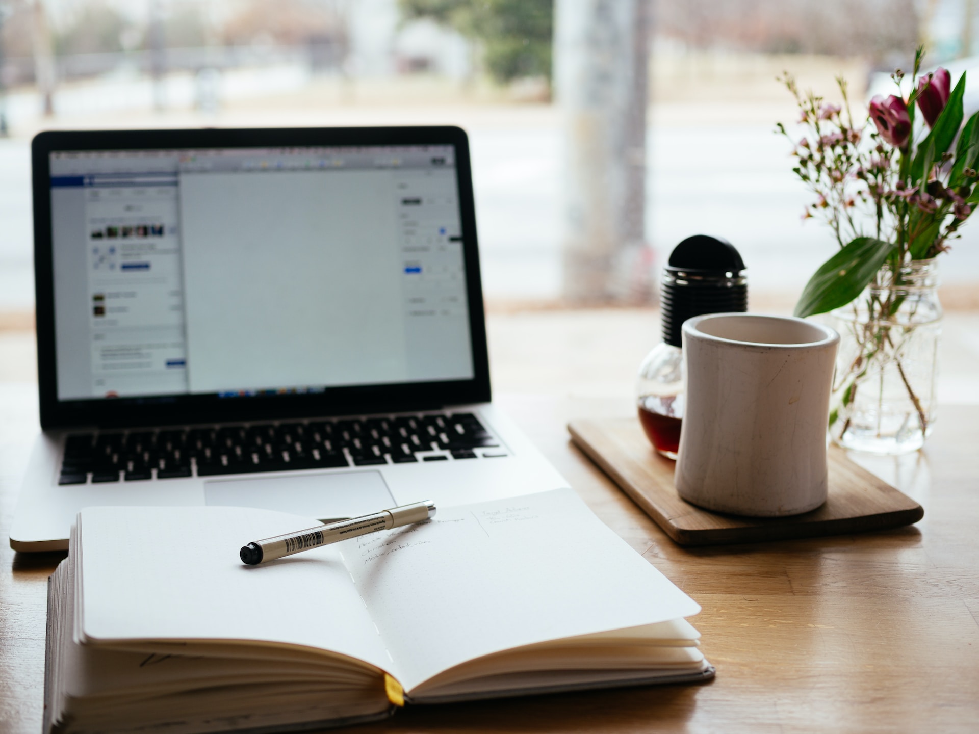 Notebook and opened laptop with a mug next to them. 