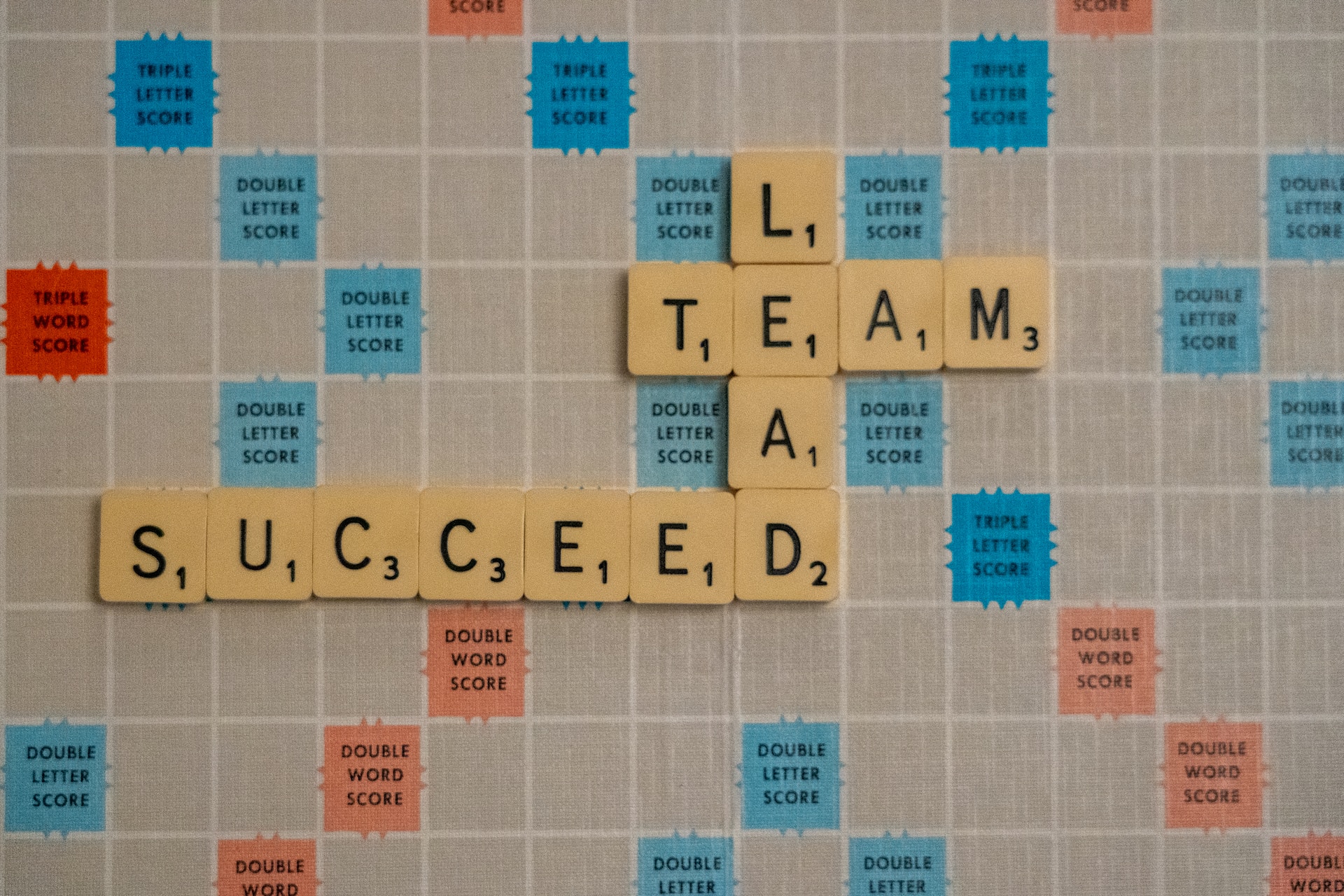 A picture of scrabble board that includes 3 words: Lead, Team, Succeed