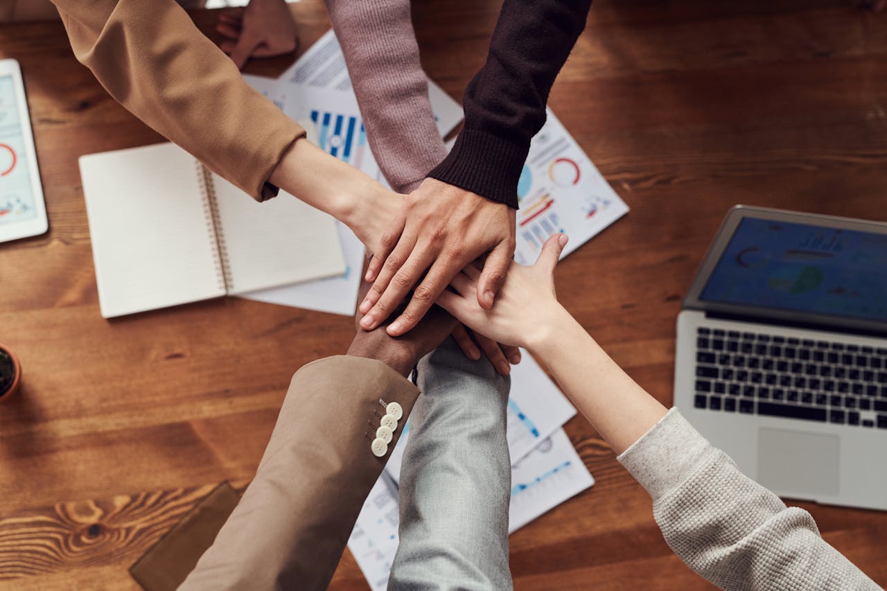 6 employees' hands all put in the middle in a circle