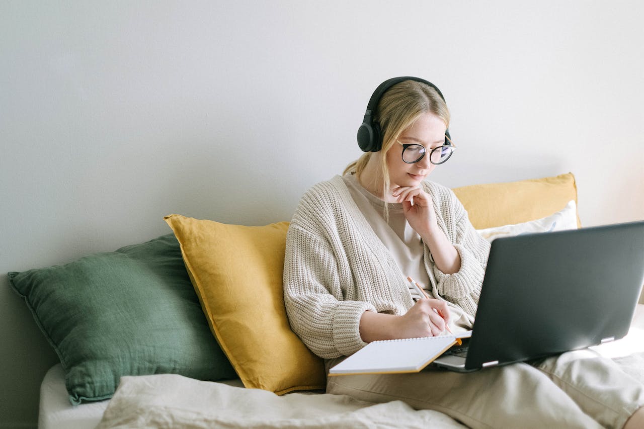girl wearing headphone and working on laptop from home